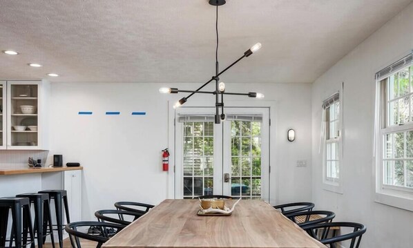 A modern dining area with a wooden table, black chairs, and a unique pendant light fixture.