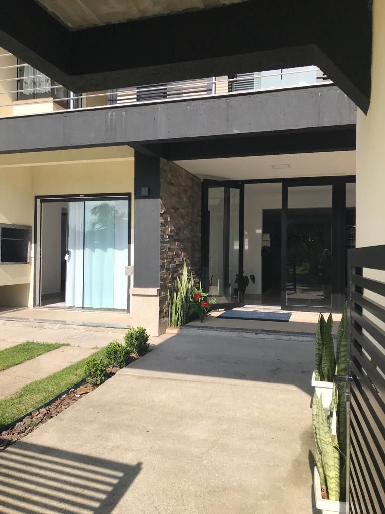 Edifício moderno com entrada coberta, porta de vidro e caminho de concreto.