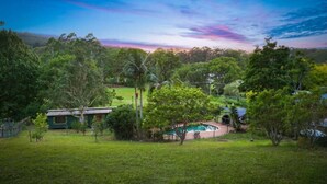A residential area with a swimming pool, a small house, and surrounding greenery.