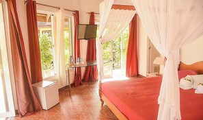 A bedroom with a bed, a TV, a desk, and a window with curtains. - Le Palme Beach Resort (Pandan)