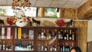 A bar area with a stone wall, wooden stools, and a variety of bottles on shelves. - Le Palme Beach Resort (Pandan)