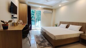 A modern hotel room with a bed, desk, chair, and a TV. - Covie Gurgaon 70 (Gurugram)