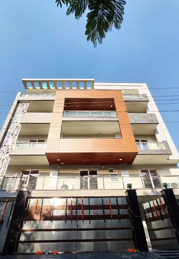 A multi-story building with balconies, a decorative gate, and a clear blue sky. - Covie Gurgaon 70 (Gurugram)