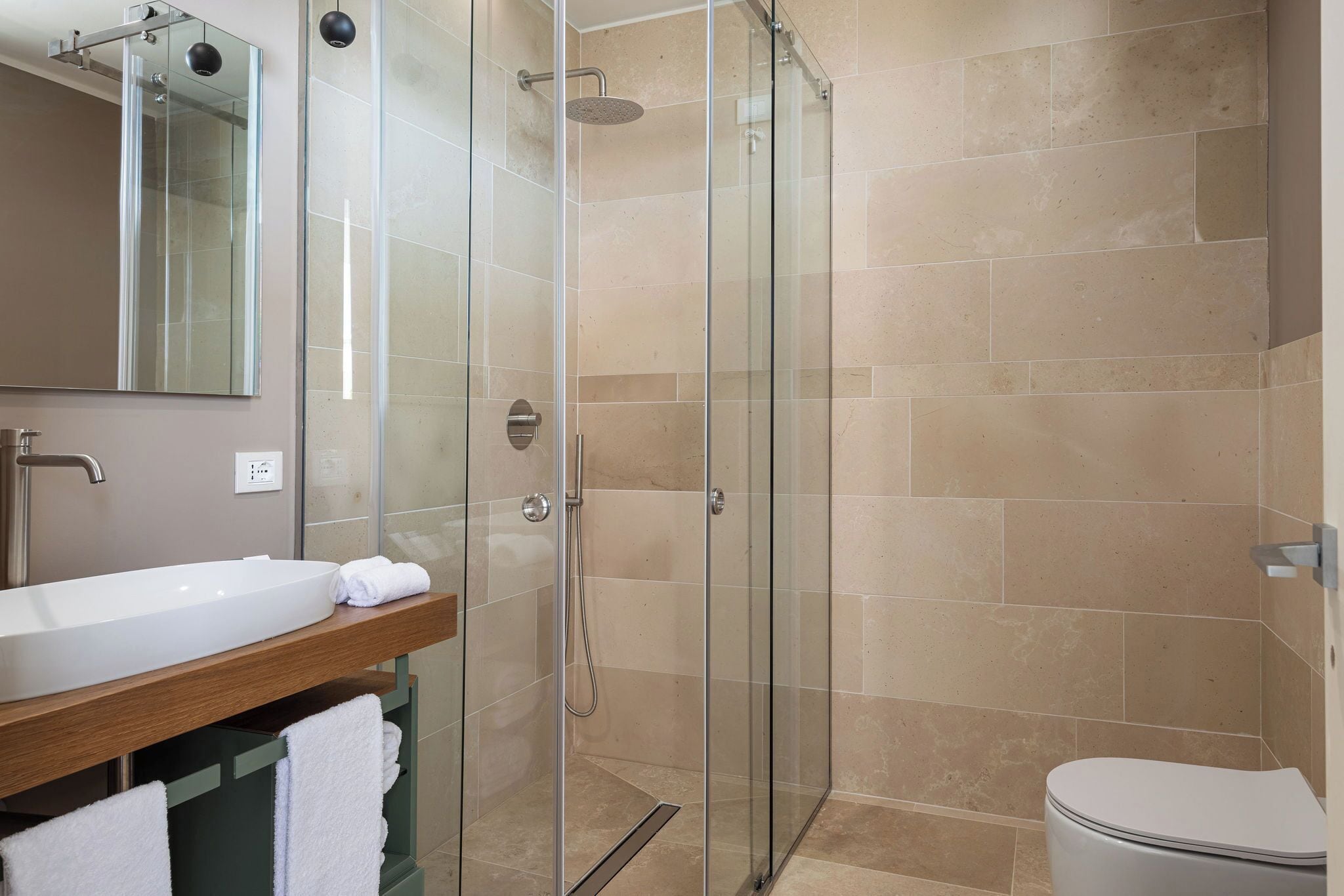 Un bagno moderno con doccia vetrata, lavandino bianco e water.