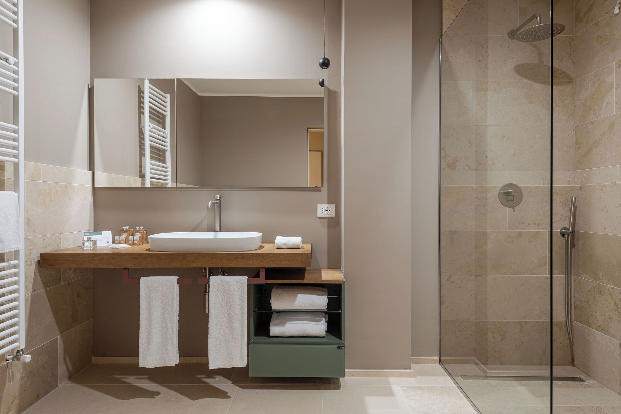 Un baño moderno con cabina de ducha de vidrio, tocador de madera con lavabo y espejo arriba.