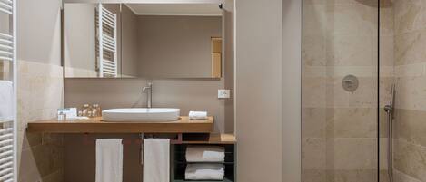 Un baño moderno con cabina de ducha de vidrio, tocador de madera con lavabo y espejo arriba.