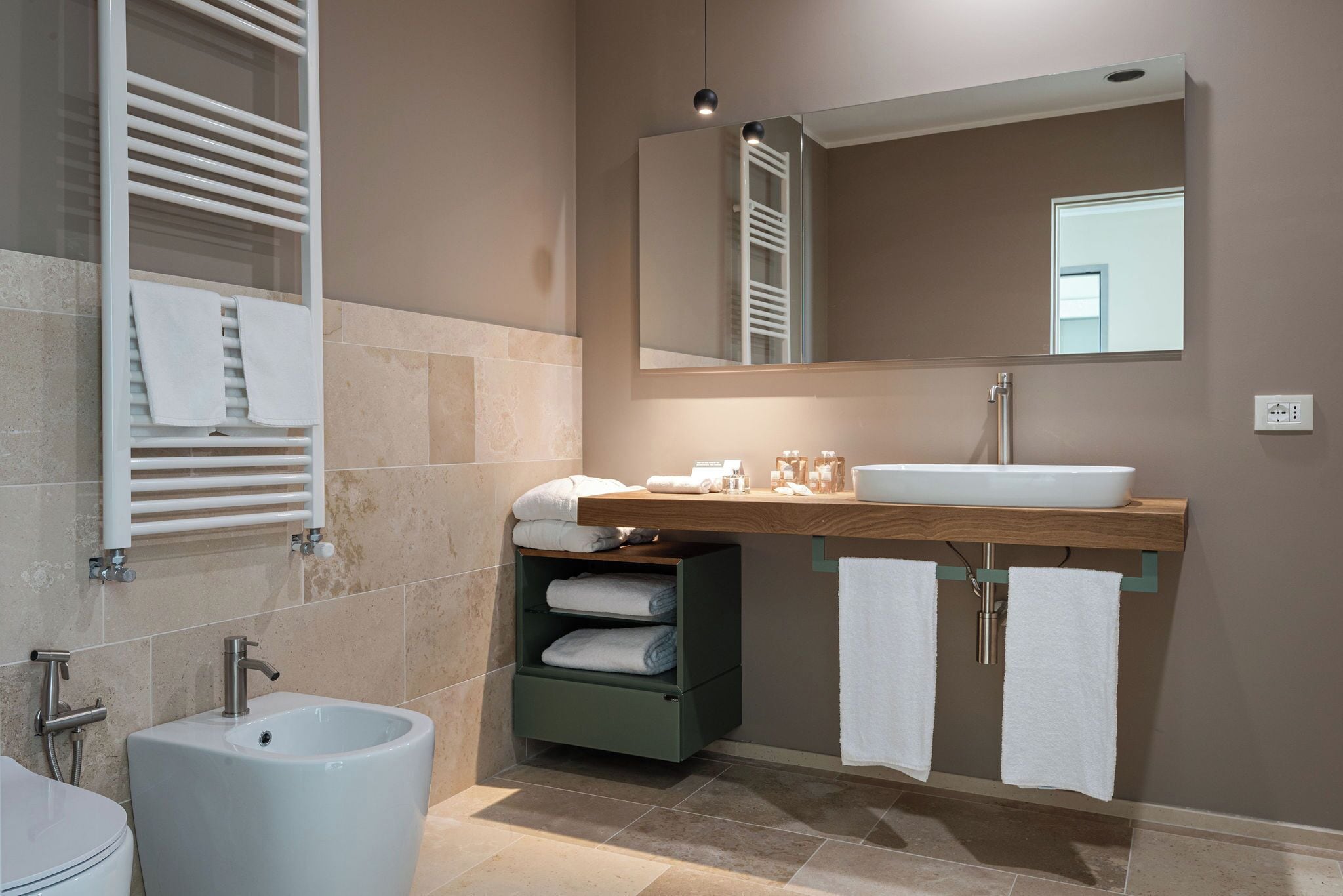 A modern bathroom with a pedestal sink, a large mirror, and a towel rack.