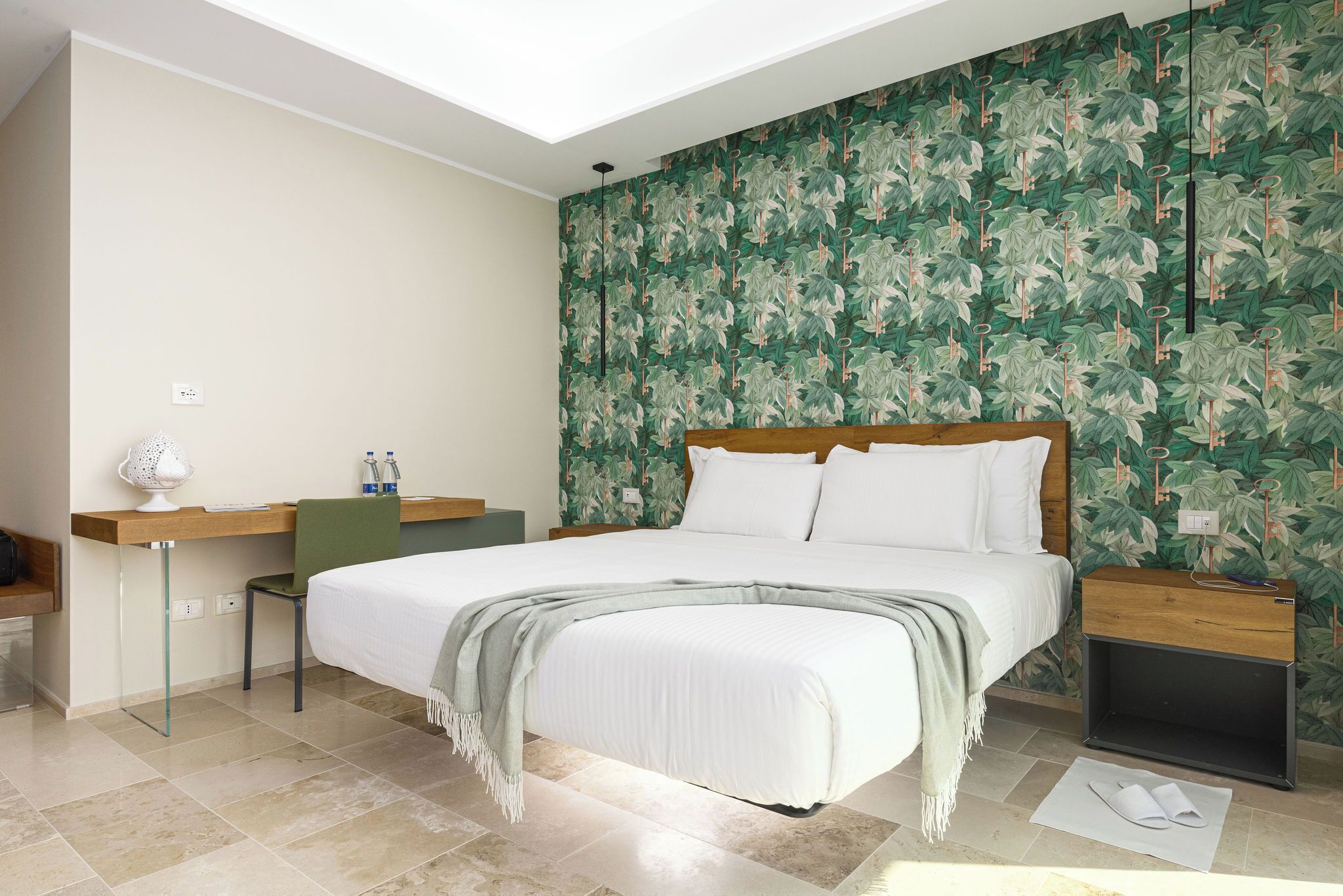 Ein modernes Hotelzimmer mit einem großen Bett, einem Schreibtisch, einem Sessel und einem Nachttisch.