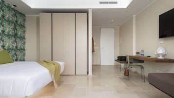 A modern hotel room with a bed, a desk, a chair, and a TV.