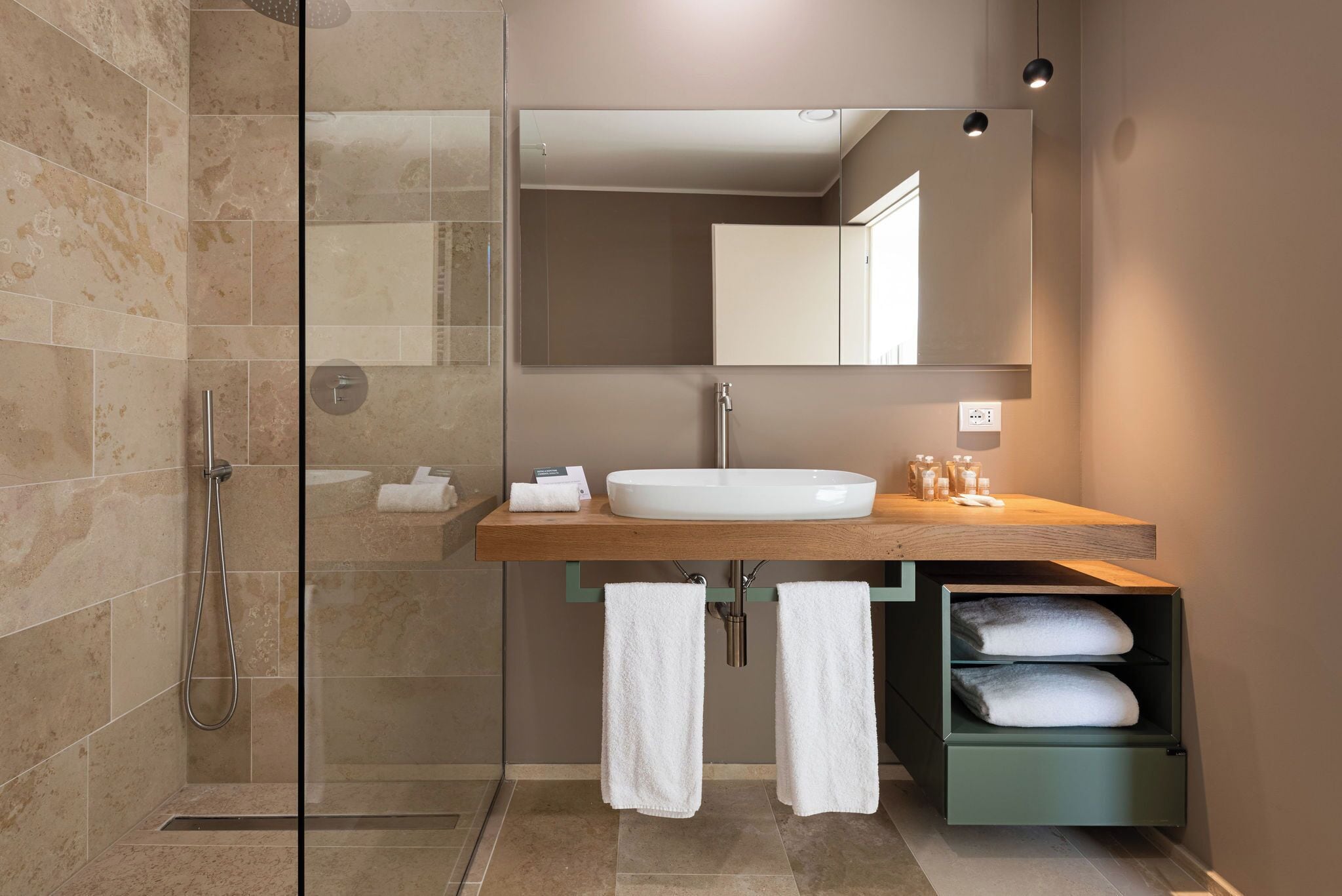 A modern bathroom with a glass shower enclosure, a wooden vanity with a sink, and a mirror.