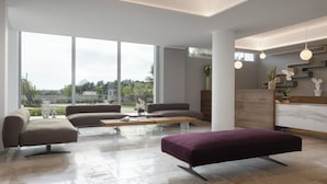 A spacious living area with large windows, a sofa set, a coffee table, and a kitchen area with modern appliances and decor. - Torre Assunta Hotel (Gallipoli)