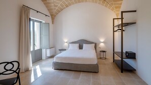 A bedroom with a bed, bedside tables, a wardrobe, and a chair. - Torre Assunta Hotel (Gallipoli)