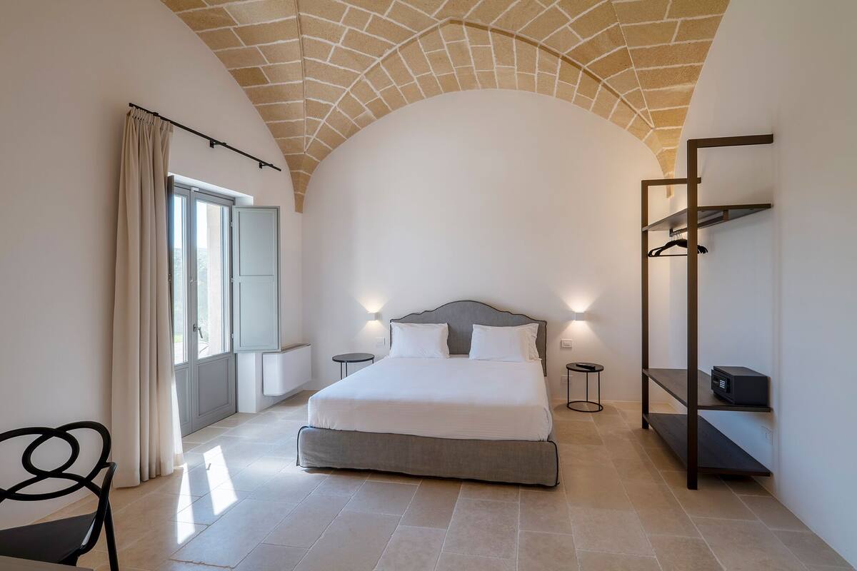 Un dormitorio con cama, mesitas de noche, armario y una silla.