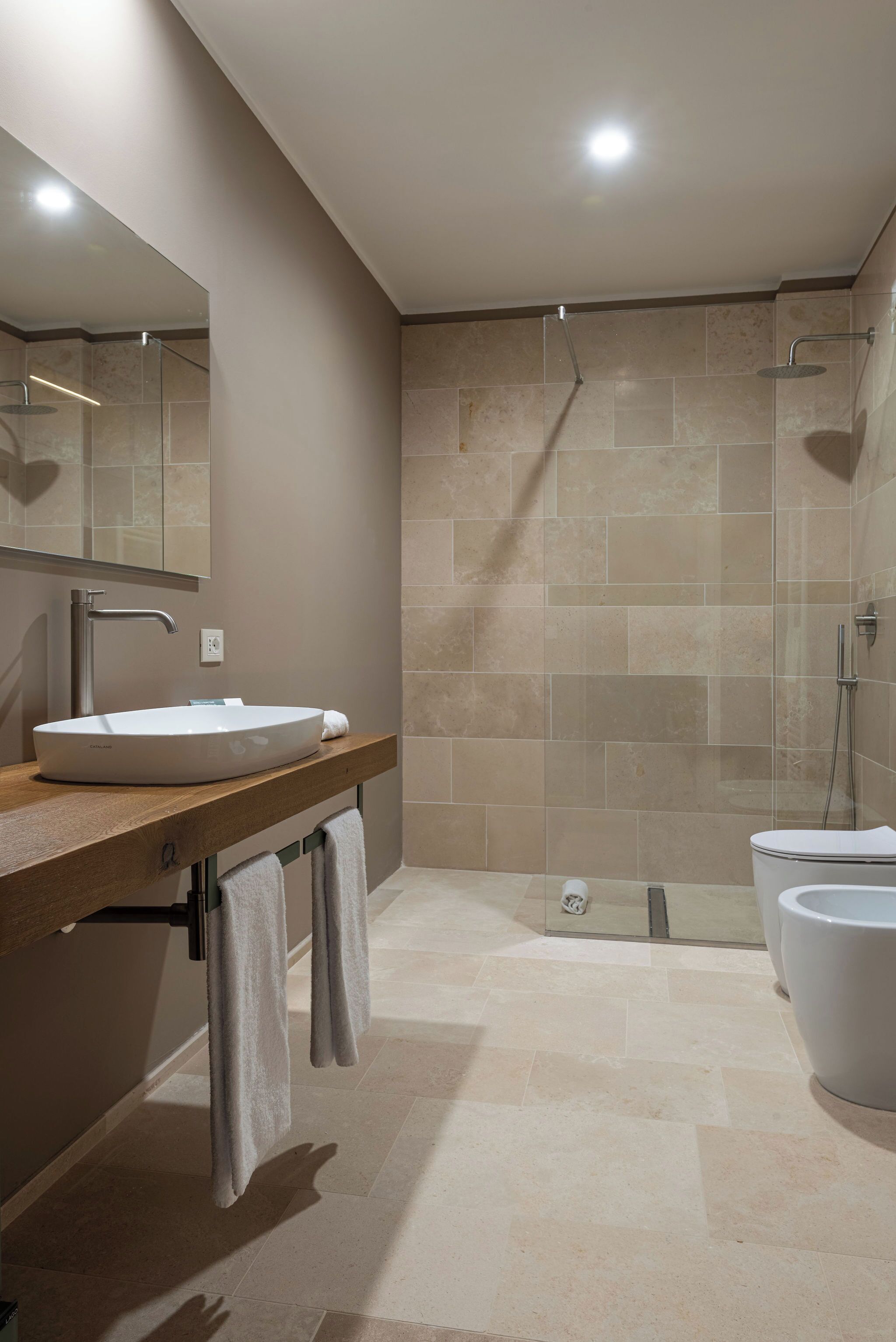 Une salle de bain moderne avec un grand lavabo, un miroir et un espace douche.