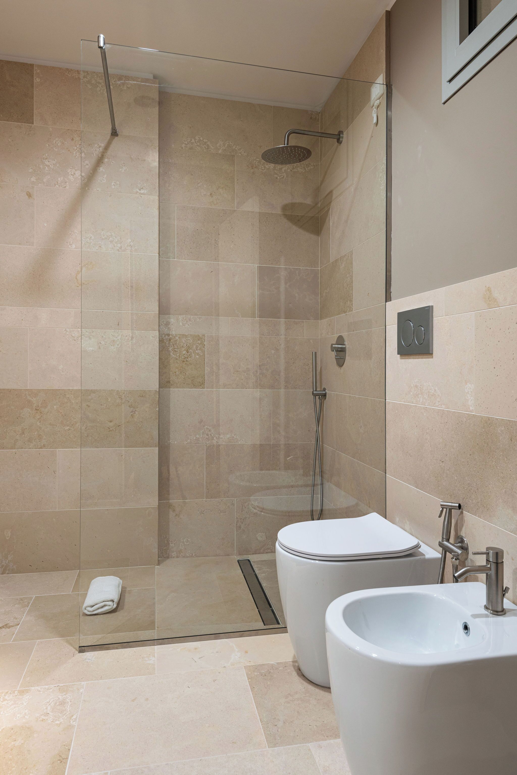 Une salle de bain moderne avec une douche à parois de verre, deux vasques blanches et un grand miroir.