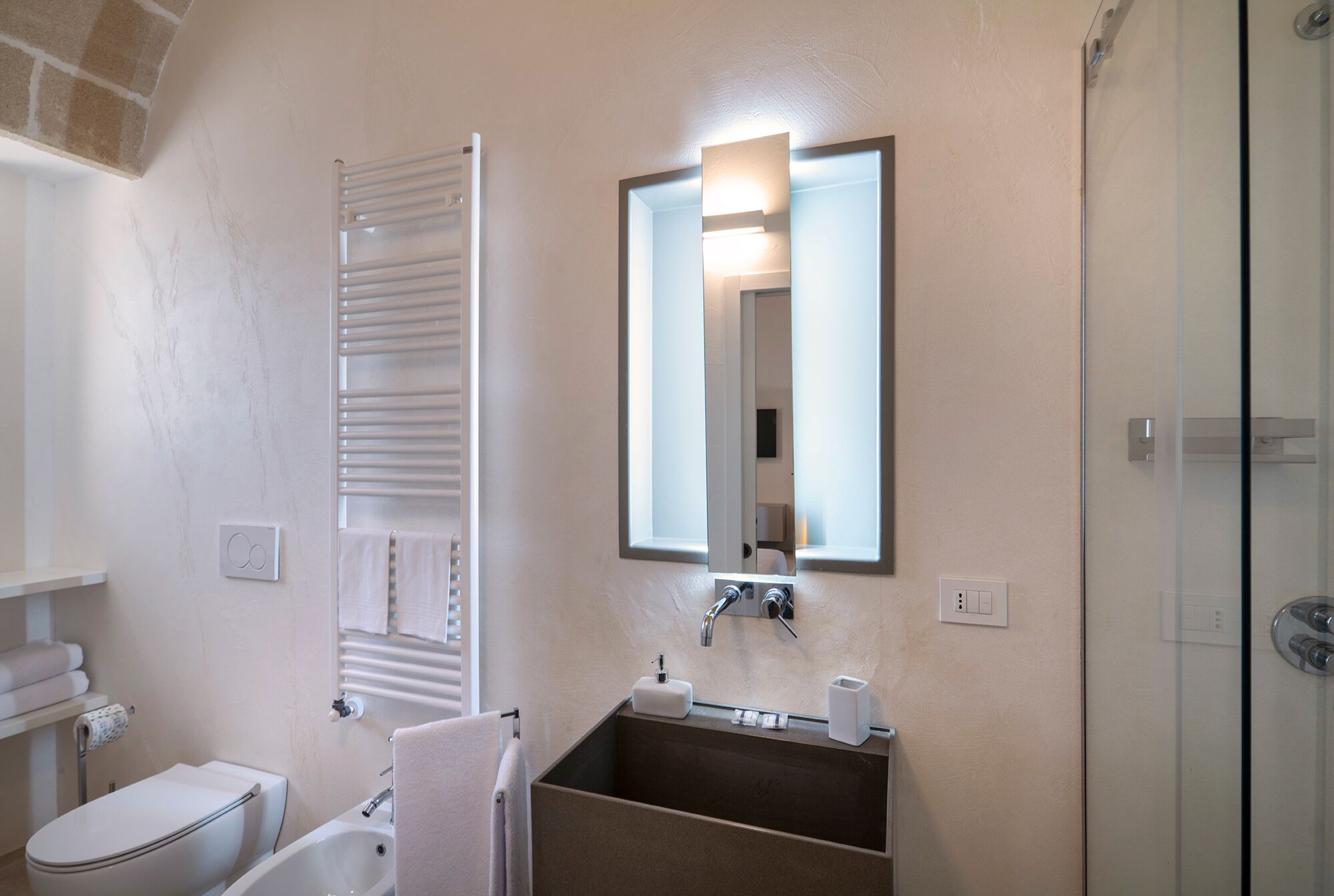Een badkamer met een toilet, een wastafel met spiegel en een douche.