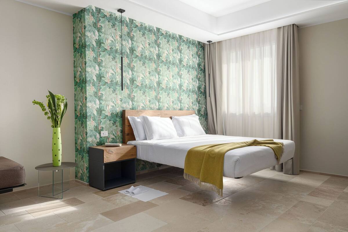 Un dormitorio moderno con una cama, una mesita de noche, una pequeña mesa y una planta verde.