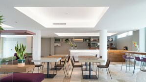 A modern restaurant with a central bar, multiple seating areas, and a visible kitchen in the background. - Torre Assunta Hotel (Gallipoli)