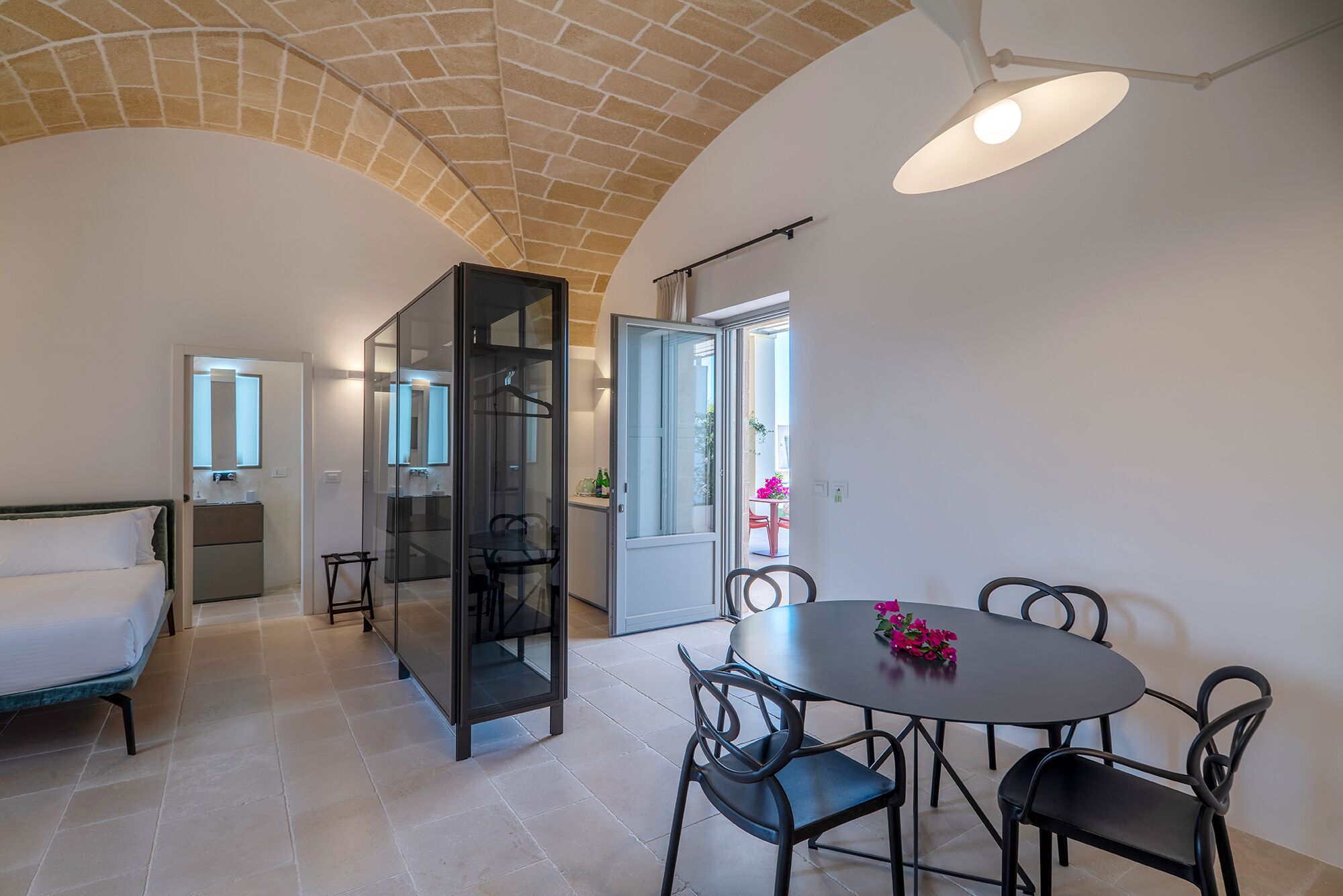 Una habitación moderna con una mesa de comedor y sillas, un sofá y un separador de vidrio.