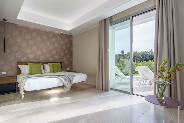 A modern bedroom with a large bed, a bedside table with a vase, and a sliding glass door leading to an outdoor area. - Torre Assunta Hotel (Gallipoli)