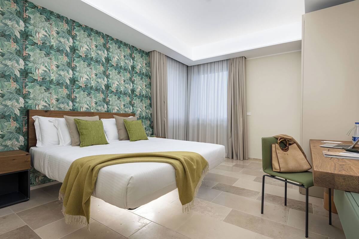 Habitación de hotel con una cama grande, un escritorio con una silla y una ventana con cortinas.