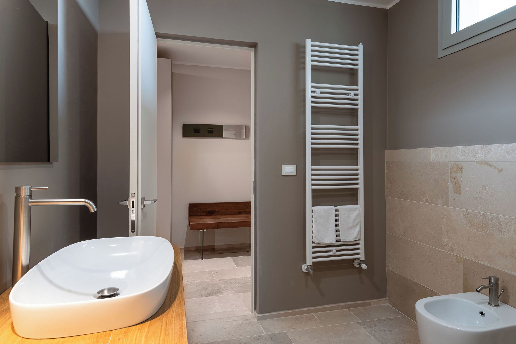 A modern bathroom with a freestanding sink, a bidet, and a towel rack.