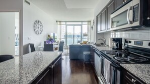 A modern kitchen with granite countertops, stainless steel appliances, and a large window providing a view of the city. - GLOBALSTAY. Bright 1Br+Den Unit in Downtown (Toronto/Canada)