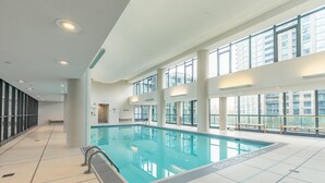 A large indoor swimming pool with clear blue water, surrounded by large windows and a tiled floor. - GLOBALSTAY. Bright 1Br+Den Unit in Downtown (Toronto/Canada)