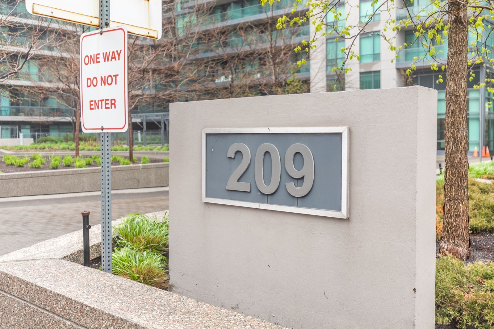 Une entrée d’immeuble avec un panneau indiquant « Sens unique, entrée interdite » et un panneau indiquant le numéro de l’immeuble, « 209 ».