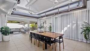 Un espace repas moderne avec une table en bois, des chaises noires et des plantes en pot.