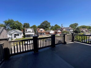 A residential area with houses, a clear sky, and a black metal fence.