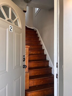 A wooden staircase with a white door marked with the number 2.