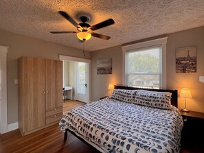 A bedroom with a bed, a ceiling fan, a desk, and a wardrobe. - Rolston 2, Two Bedroom Unit near Xavier, Downtown (Cincinnati)