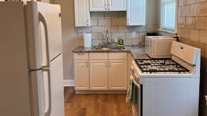 A kitchen with white cabinets, a refrigerator, a microwave, and a stove.