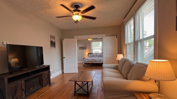 A living room with a television, sofa, coffee table, and a ceiling fan.