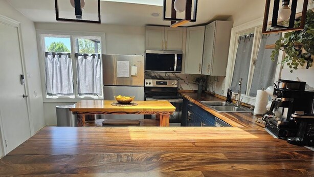 A kitchen with a wooden island, stainless steel appliances, and a view of the outdoors.