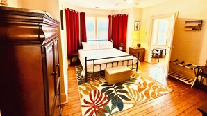 A bedroom with a bed, a nightstand, a dresser, a window with curtains, and a ceiling fan.