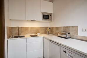 A modern kitchen with white cabinetry, a built-in microwave, a toaster, and a dishwasher. - Los Apartamentos del Palacio (Casalarreina)
