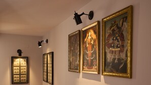 Un couloir au sol carrelé, dont les murs sont ornés d’œuvres d’art encadrées.