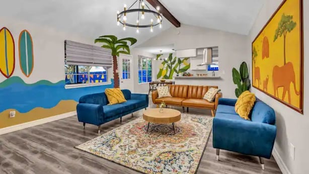A living room with blue sofas, a coffee table, and a colorful rug. - Beautiful 5BR Houston Designer Villa (Houston)