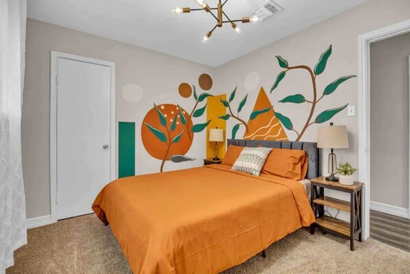 A bedroom with a bed, a nightstand, a lamp, and a wall mural. - Beautiful 5BR Houston Designer Villa (Houston)
