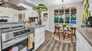 A modern kitchen with a central island, built-in oven, and a dining area with a round table and chairs. - Beautiful 5BR Houston Designer Villa (Houston)