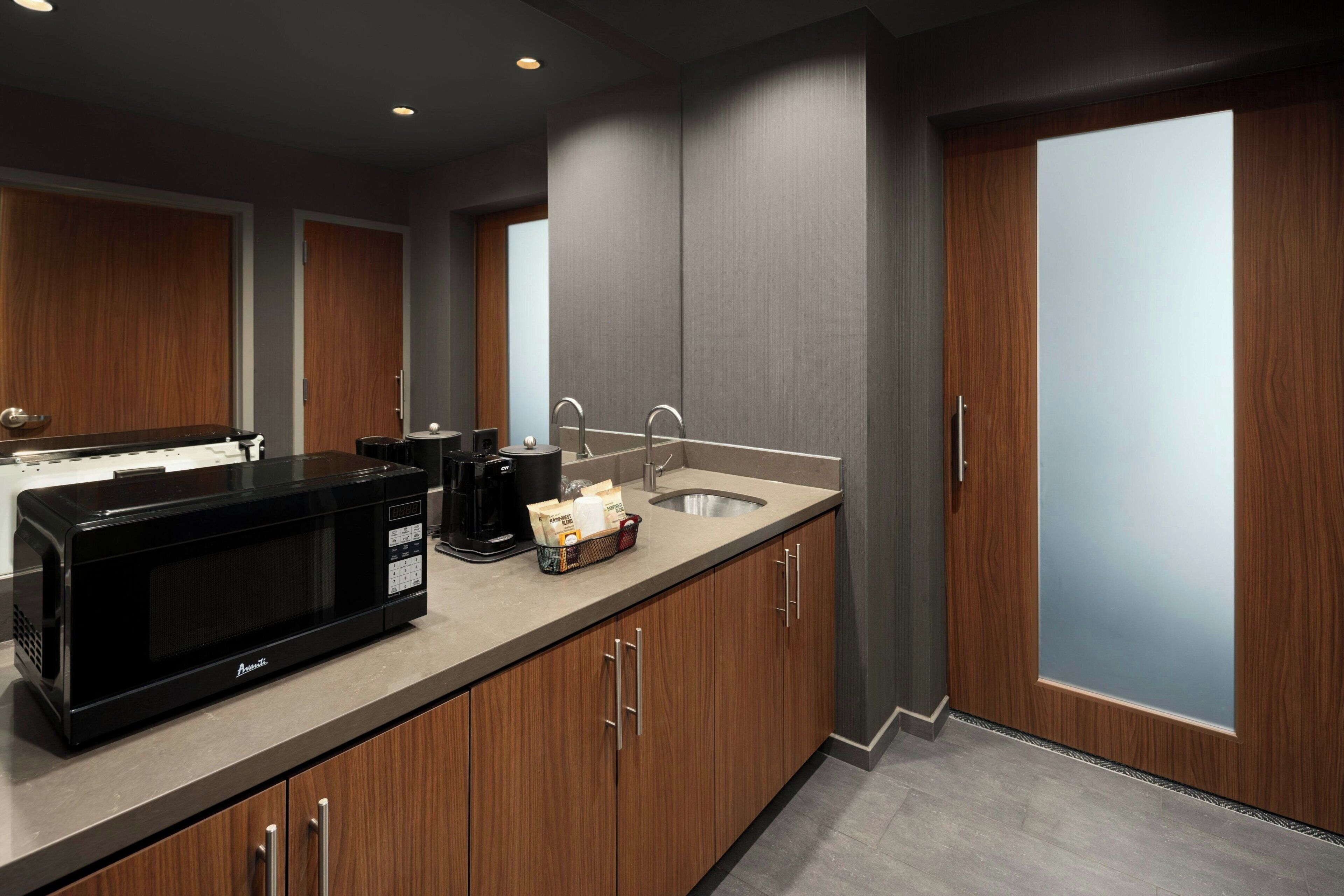 A modern kitchen with a built-in microwave, coffee maker, and a sink.
