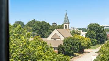 A church with a steeple and a bell tower, surrounded by trees and a clear sky.