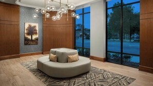 A modern lobby with a round seating area, a large window with a view of the street, and a chandelier. - Courtyard by Marriott Gainesville GA (Gainesville)