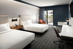 A hotel room with two beds, a desk, a chair, a lamp, and a view of the outdoors. - Courtyard by Marriott Gainesville GA (Gainesville)
