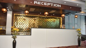 A reception area with a 'RECEPTION' sign, a decorative metal fence, and two vases with flowers.