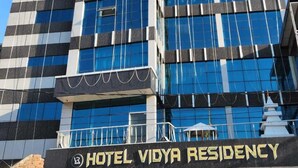 A modern hotel building with a prominent sign reading "HOTEL VIDYA RESIDENCY".