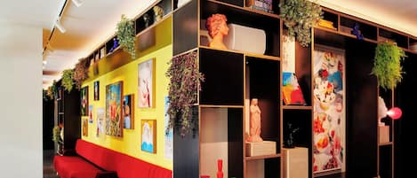 A modern interior with a red sofa, black and yellow walls, and shelves with books, decorative items, and plants.