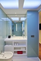 Un bagno moderno con doccia vetrata, un mobile lavabo bianco con specchio e lavandino incassato.